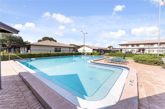 community pool with a patio area and fence