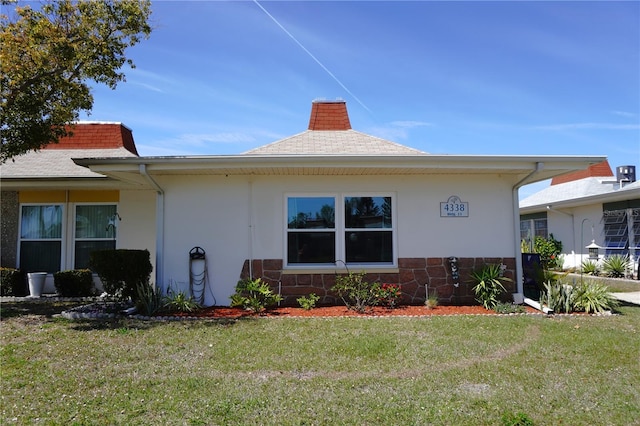 view of property exterior featuring stone siding, a lawn, and stucco siding