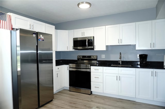 kitchen with a sink, light wood-type flooring, white cabinetry, and stainless steel appliances