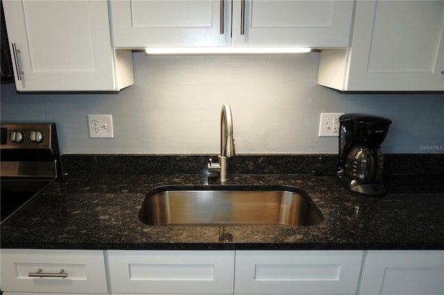 kitchen with white cabinetry, electric stove, dark stone counters, and a sink