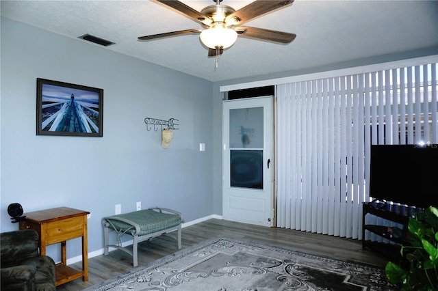 interior space with visible vents, a ceiling fan, a textured ceiling, wood finished floors, and baseboards