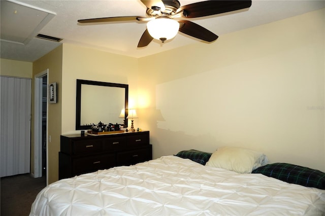 carpeted bedroom featuring visible vents, attic access, and a ceiling fan