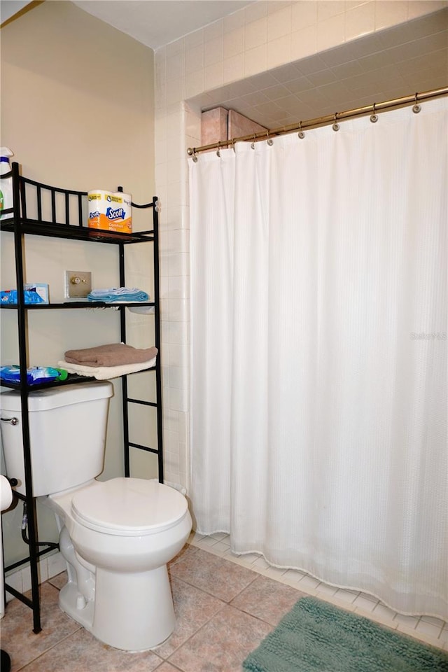 bathroom with a shower with curtain, toilet, and tile patterned flooring