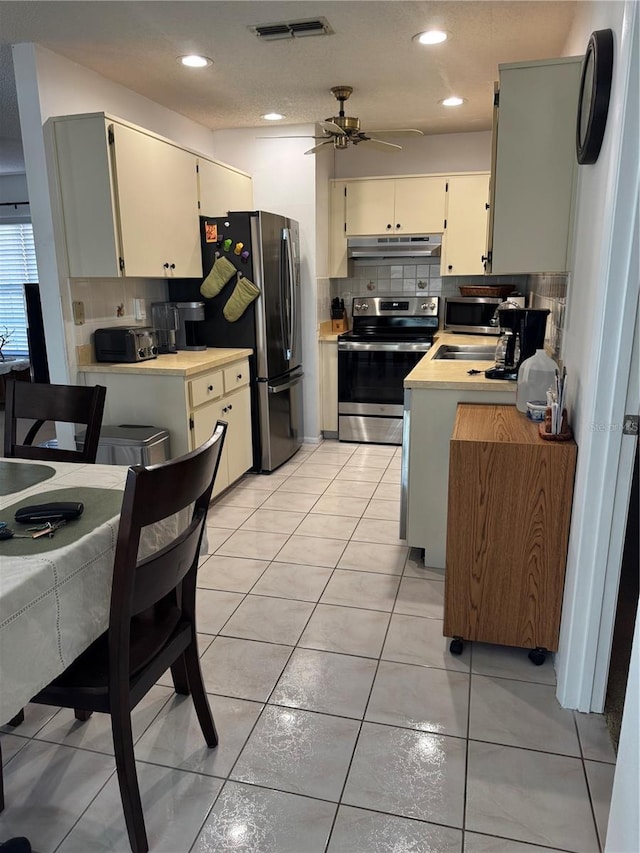 kitchen with visible vents, under cabinet range hood, tasteful backsplash, appliances with stainless steel finishes, and light countertops