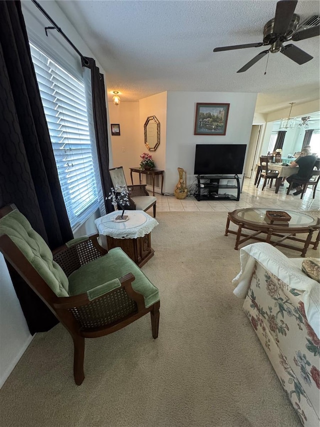 living room featuring light tile patterned floors, light carpet, a textured ceiling, and ceiling fan