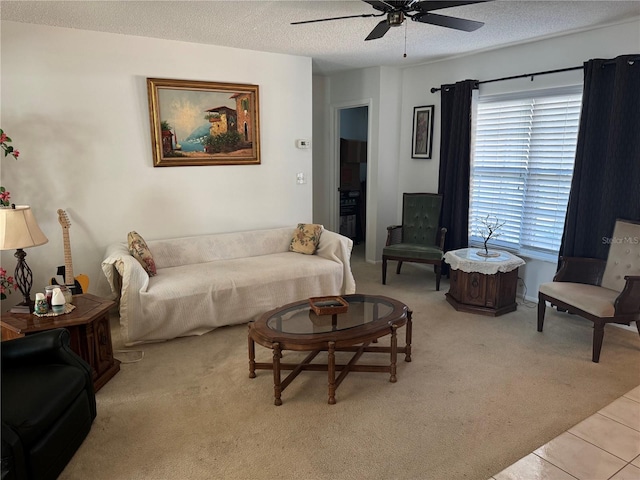 living room featuring light tile patterned floors, light colored carpet, ceiling fan, and a textured ceiling