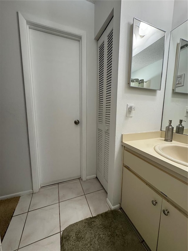 bathroom with tile patterned flooring, vanity, and a closet