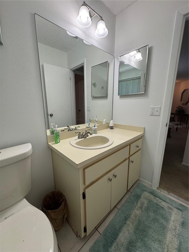 bathroom with tile patterned flooring, a textured ceiling, toilet, and vanity