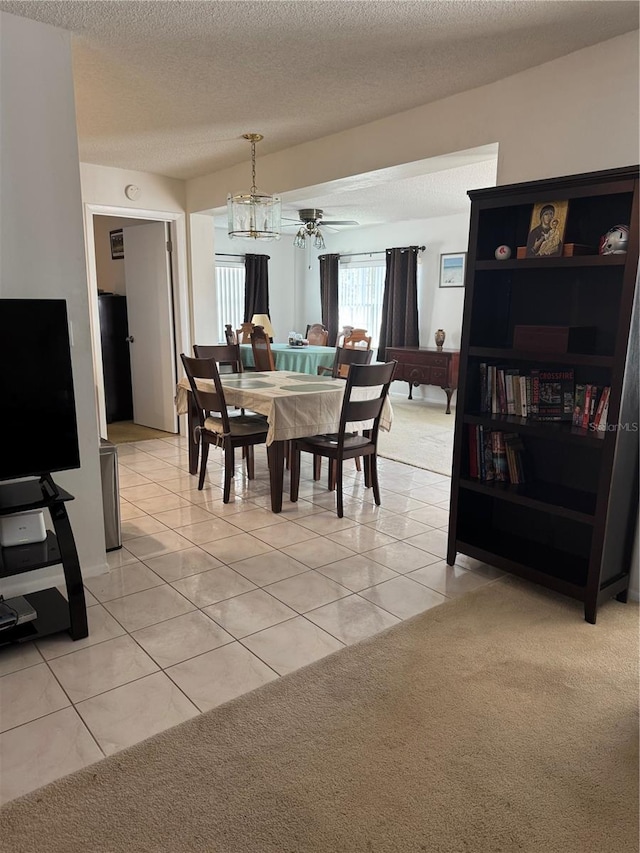 dining area with ceiling fan, light carpet, a textured ceiling, and light tile patterned flooring