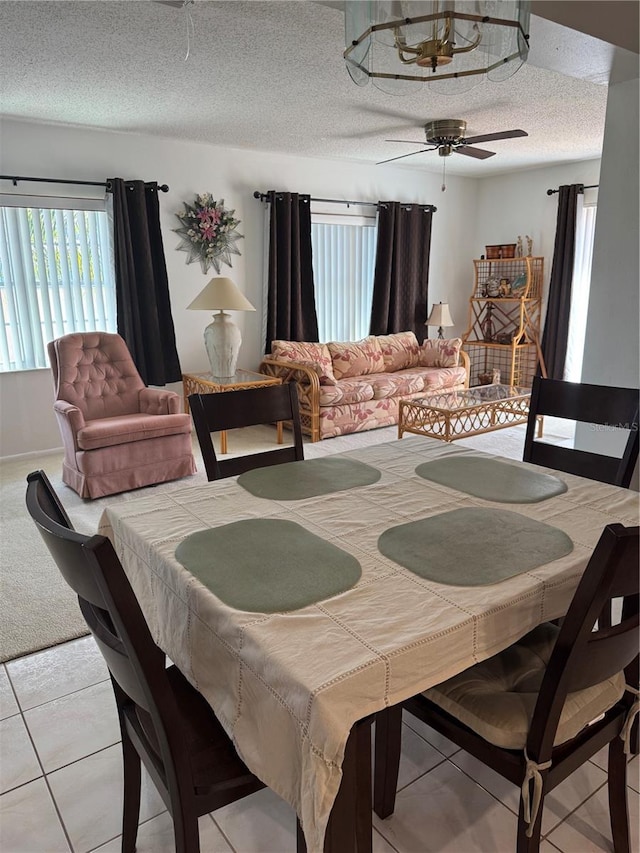 carpeted dining space featuring tile patterned floors, a textured ceiling, and ceiling fan