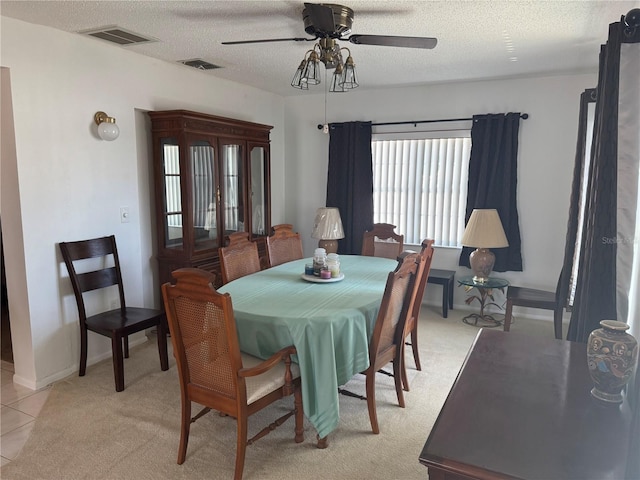 dining room featuring light tile patterned floors, visible vents, a textured ceiling, and ceiling fan