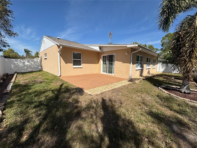 back of property featuring a yard, a fenced backyard, stucco siding, and a patio