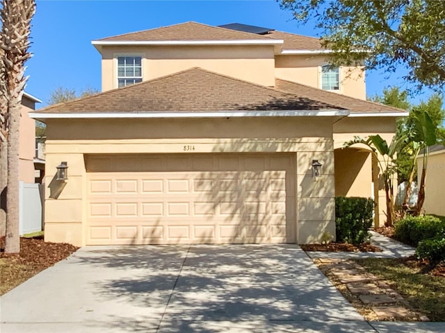 traditional-style house with stucco siding, concrete driveway, a garage, and a shingled roof