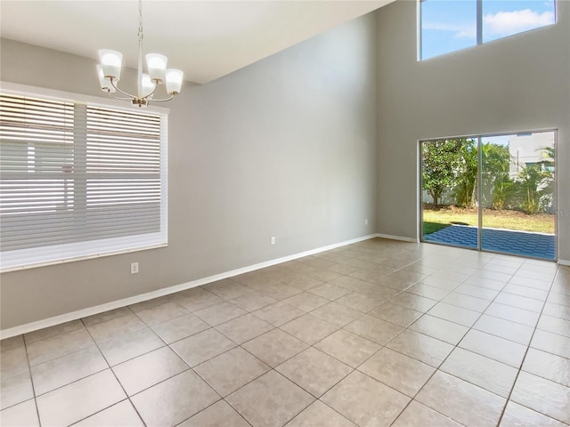 unfurnished room featuring a wealth of natural light, light tile patterned floors, baseboards, and an inviting chandelier