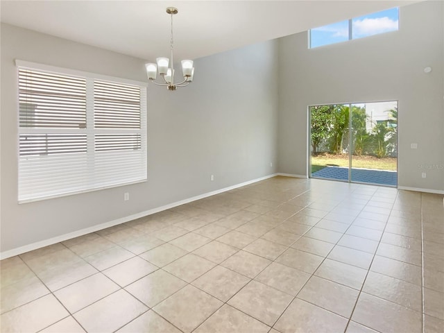 spare room featuring light tile patterned floors, baseboards, plenty of natural light, and a chandelier