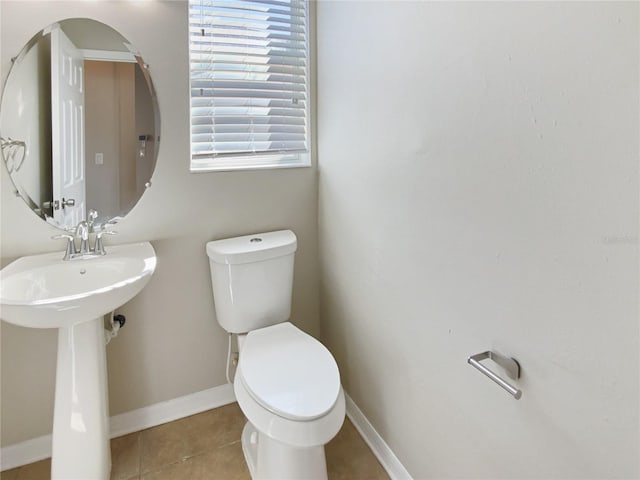 bathroom with tile patterned floors, toilet, baseboards, and a sink