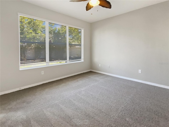 carpeted spare room featuring baseboards and a ceiling fan