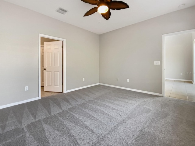 carpeted spare room featuring visible vents, baseboards, and a ceiling fan