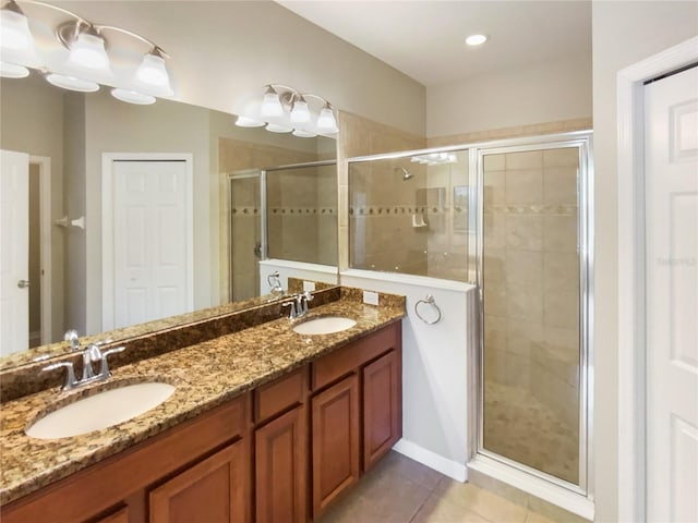 bathroom with tile patterned flooring, double vanity, a stall shower, and a sink