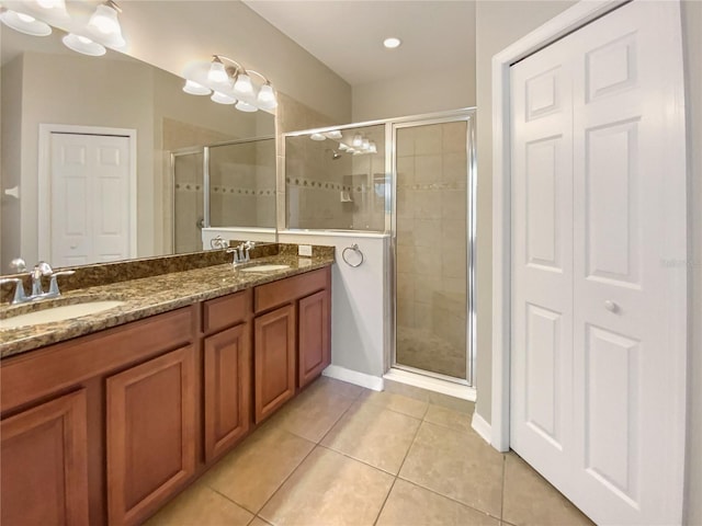 bathroom featuring tile patterned floors, a stall shower, double vanity, and a sink