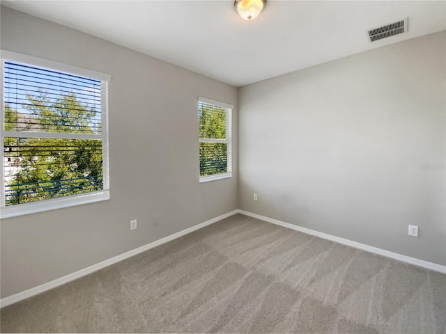 carpeted spare room featuring visible vents and baseboards