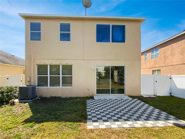 rear view of property with stucco siding, a gate, a patio, central AC, and a yard