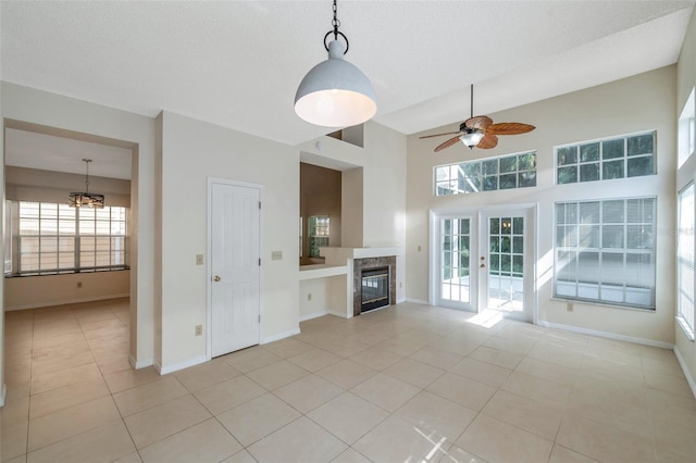 5014 Sterling Manor Dr, Tampa, FL 33647 - unfurnished living room featuring light tile patterned flooring, a ceiling fan, a glass covered fireplace, a chandelier, and baseboards