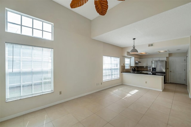 5014 Sterling Manor Dr, Tampa, FL 33647 - kitchen with dark countertops, light tile patterned flooring, a peninsula, stainless steel fridge with ice dispenser, and ceiling fan