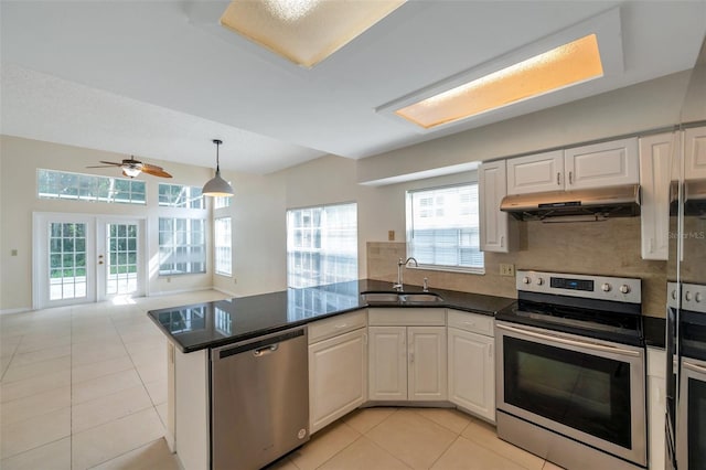 5014 Sterling Manor Dr, Tampa, FL 33647 - kitchen featuring stainless steel appliances, under cabinet range hood, a sink, a peninsula, and light tile patterned floors