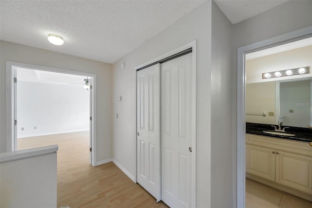 5014 Sterling Manor Dr, Tampa, FL 33647 - hallway with a textured ceiling, light wood-style flooring, a sink, and baseboards