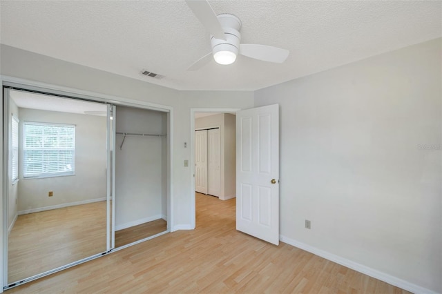 5014 Sterling Manor Dr, Tampa, FL 33647 - unfurnished bedroom with light wood-type flooring, a closet, baseboards, a textured ceiling, and a ceiling fan