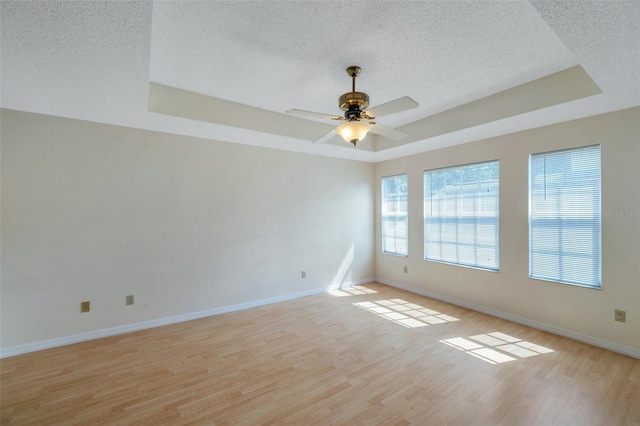 5014 Sterling Manor Dr, Tampa, FL 33647 - unfurnished room with a tray ceiling, a textured ceiling, light wood-style floors, baseboards, and a ceiling fan