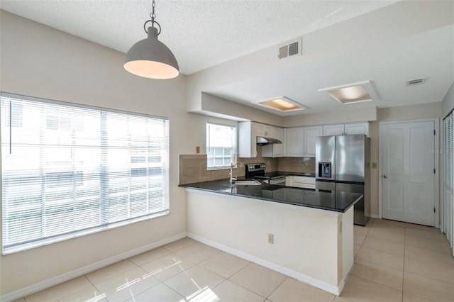 5014 Sterling Manor Dr, Tampa, FL 33647 - kitchen with stainless steel appliances, a sink, dark countertops, under cabinet range hood, and a peninsula