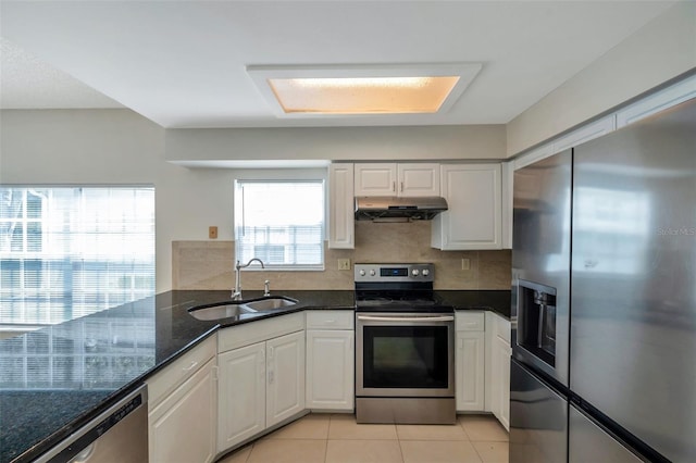 5014 Sterling Manor Dr, Tampa, FL 33647 - kitchen featuring appliances with stainless steel finishes, a sink, under cabinet range hood, light tile patterned floors, and dark stone countertops