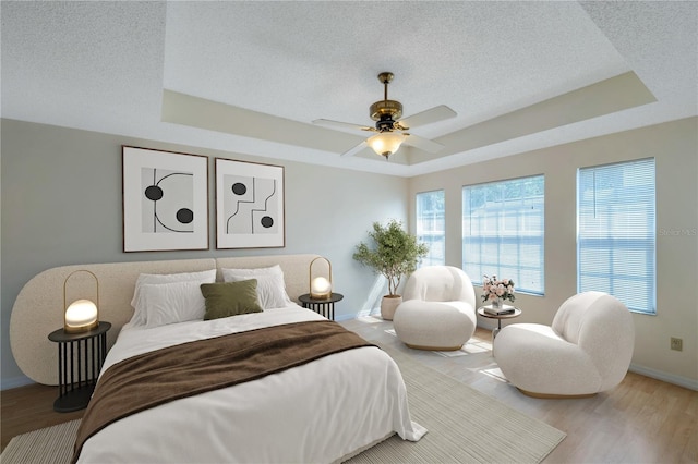5014 Sterling Manor Dr, Tampa, FL 33647 - bedroom featuring a raised ceiling, a textured ceiling, baseboards, wood finished floors, and a ceiling fan