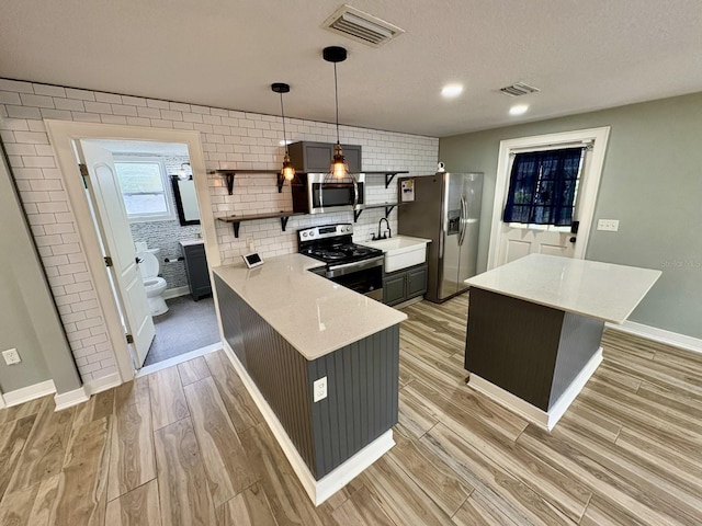 kitchen featuring visible vents, backsplash, light wood-type flooring, appliances with stainless steel finishes, and a sink