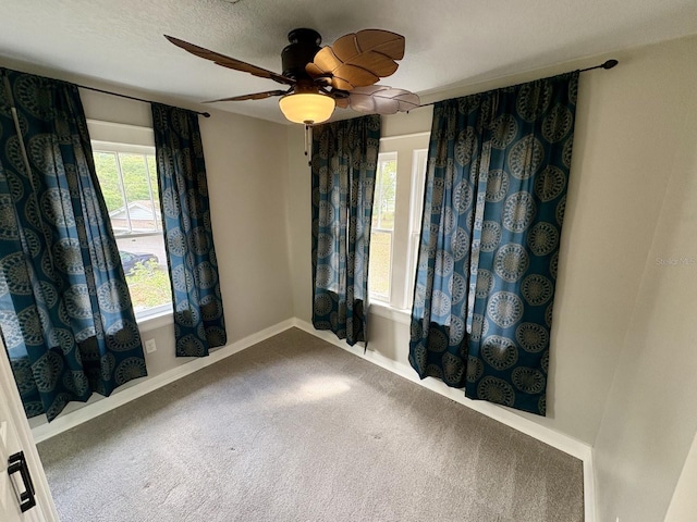 carpeted empty room with ceiling fan and baseboards