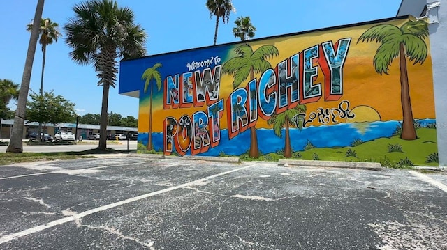 community / neighborhood sign featuring uncovered parking