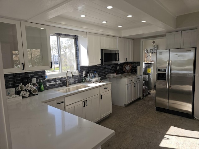 kitchen with a sink, a raised ceiling, tasteful backsplash, and stainless steel appliances