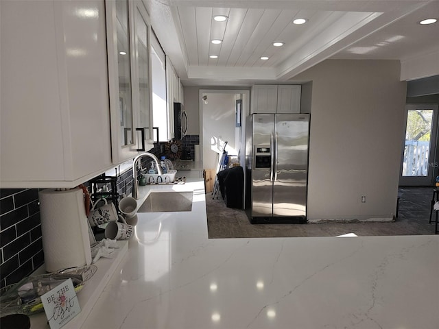 kitchen with light stone counters, a tray ceiling, a sink, gray cabinetry, and stainless steel appliances