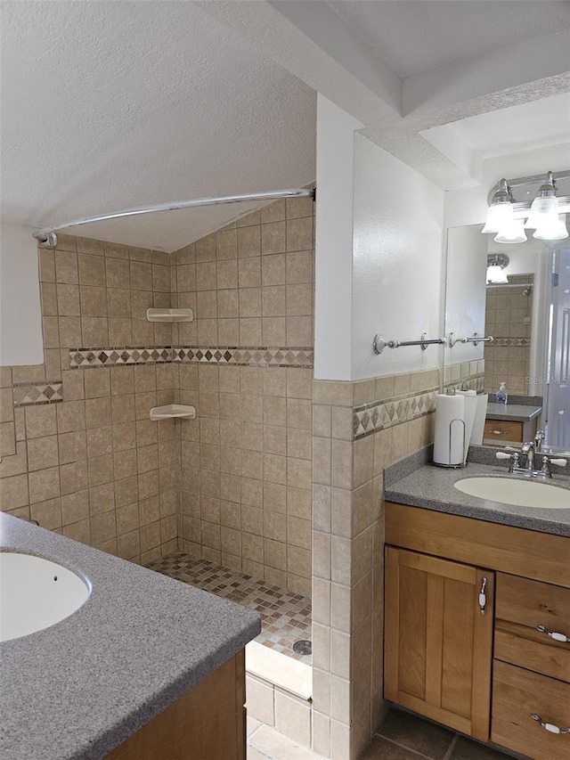 bathroom featuring tile patterned floors, a textured ceiling, a tile shower, tile walls, and vanity