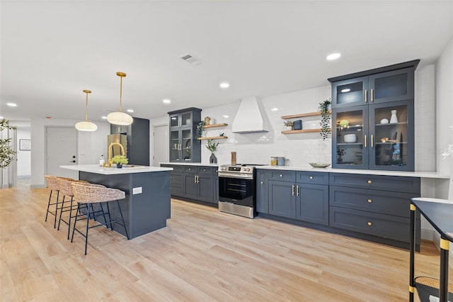 kitchen with visible vents, light wood finished floors, open shelves, stainless steel appliances, and custom range hood