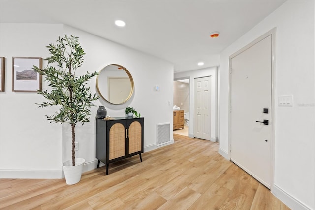 corridor with light wood-type flooring, visible vents, baseboards, and recessed lighting