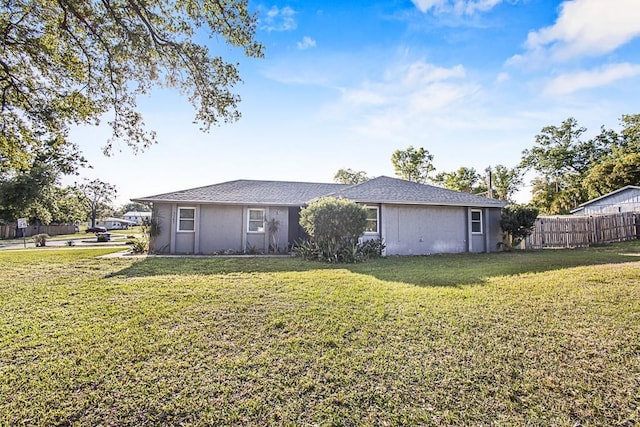 rear view of house featuring a yard, stucco siding, and fence