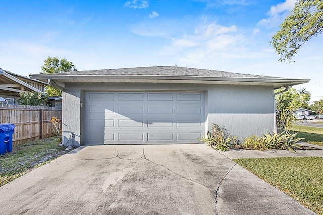 garage featuring driveway and fence