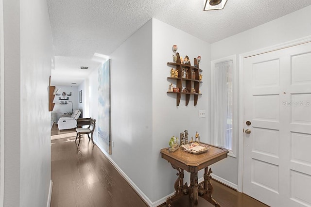 entrance foyer with dark wood-type flooring, baseboards, visible vents, and a textured ceiling