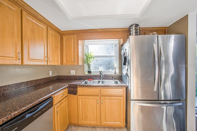 kitchen with a sink, stainless steel appliances, and dark stone counters