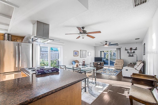 kitchen featuring wood finished floors, visible vents, island exhaust hood, freestanding refrigerator, and ceiling fan