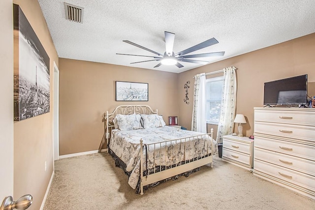 bedroom featuring a textured ceiling, baseboards, visible vents, and light carpet