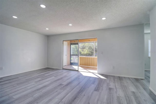 spare room with recessed lighting, a textured ceiling, baseboards, and wood finished floors